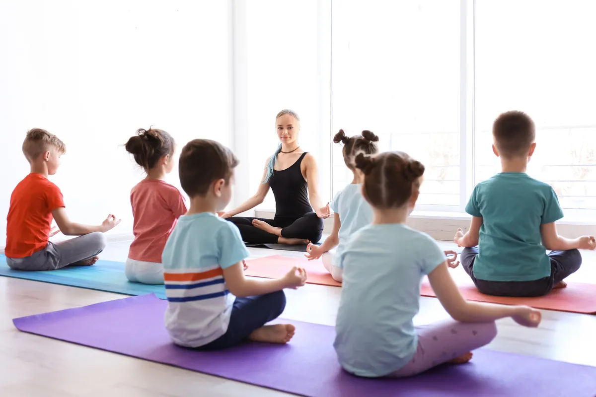 Helen Hansen Bewegungsförderung – Yoga-Kurse – Kleine Kinder und ihre Lehrerin praktizieren Yoga im Fitnessstudio